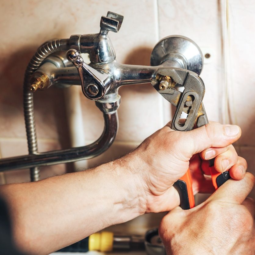 manos de fontanero apruietan rosca de grifo en bañera